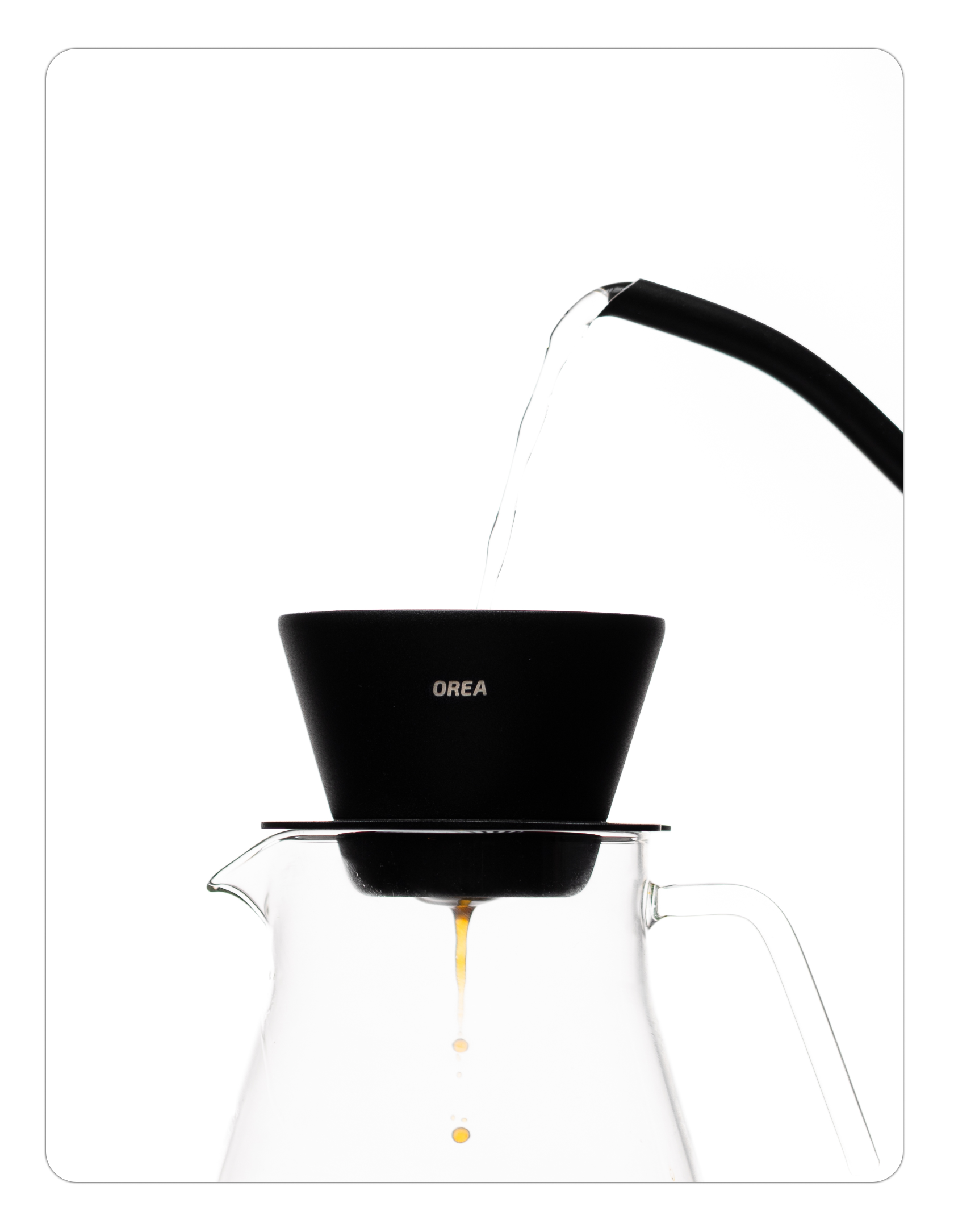 Water being poured from a thin-necked kettle into the Orea brewer, with fresh coffee dripping into a glass carafe below.