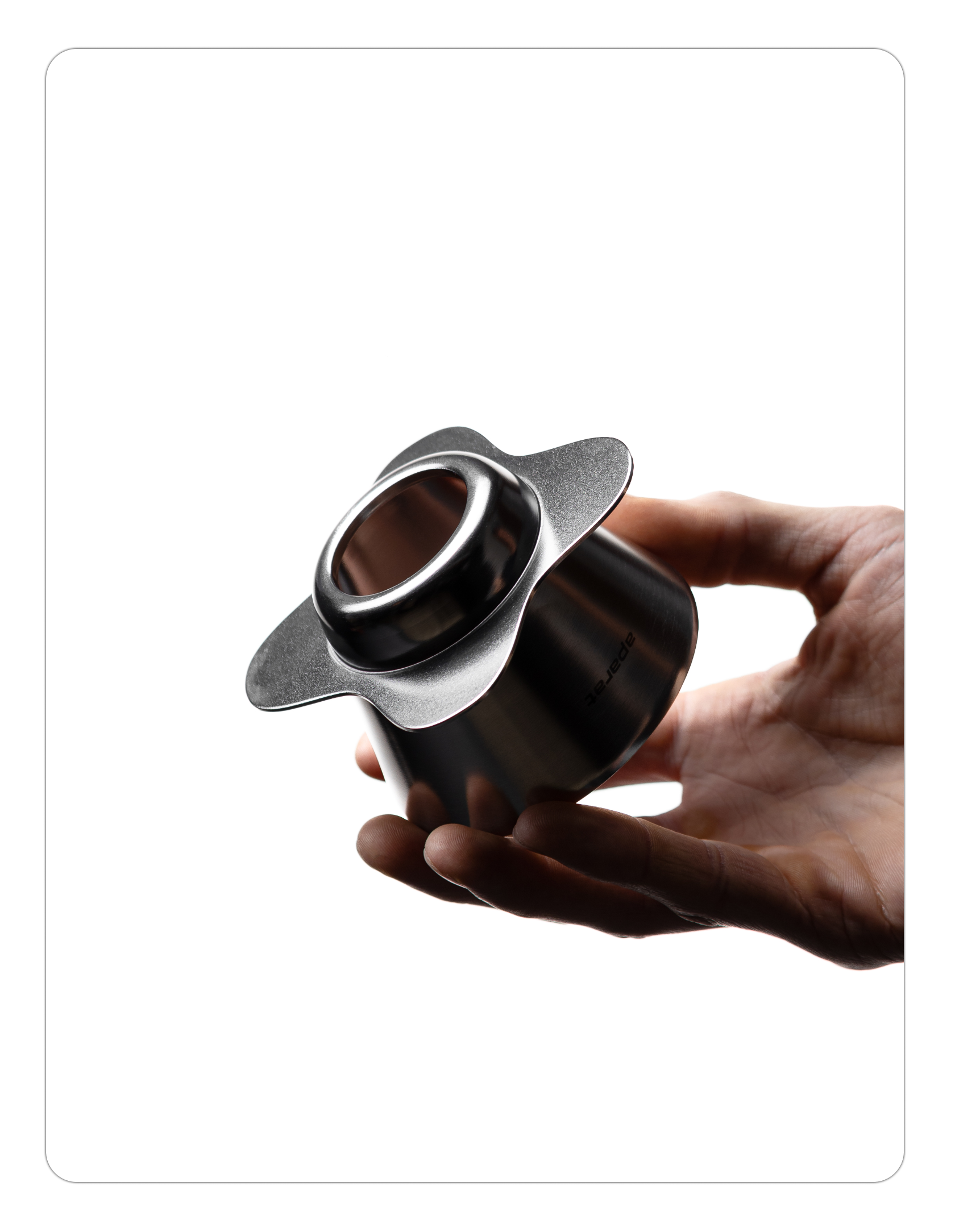 A person holding the silver Orea O1 brewer upside down, showing the circular bottom opening and the smooth, industrial raw steel finish of the petal-shaped base.