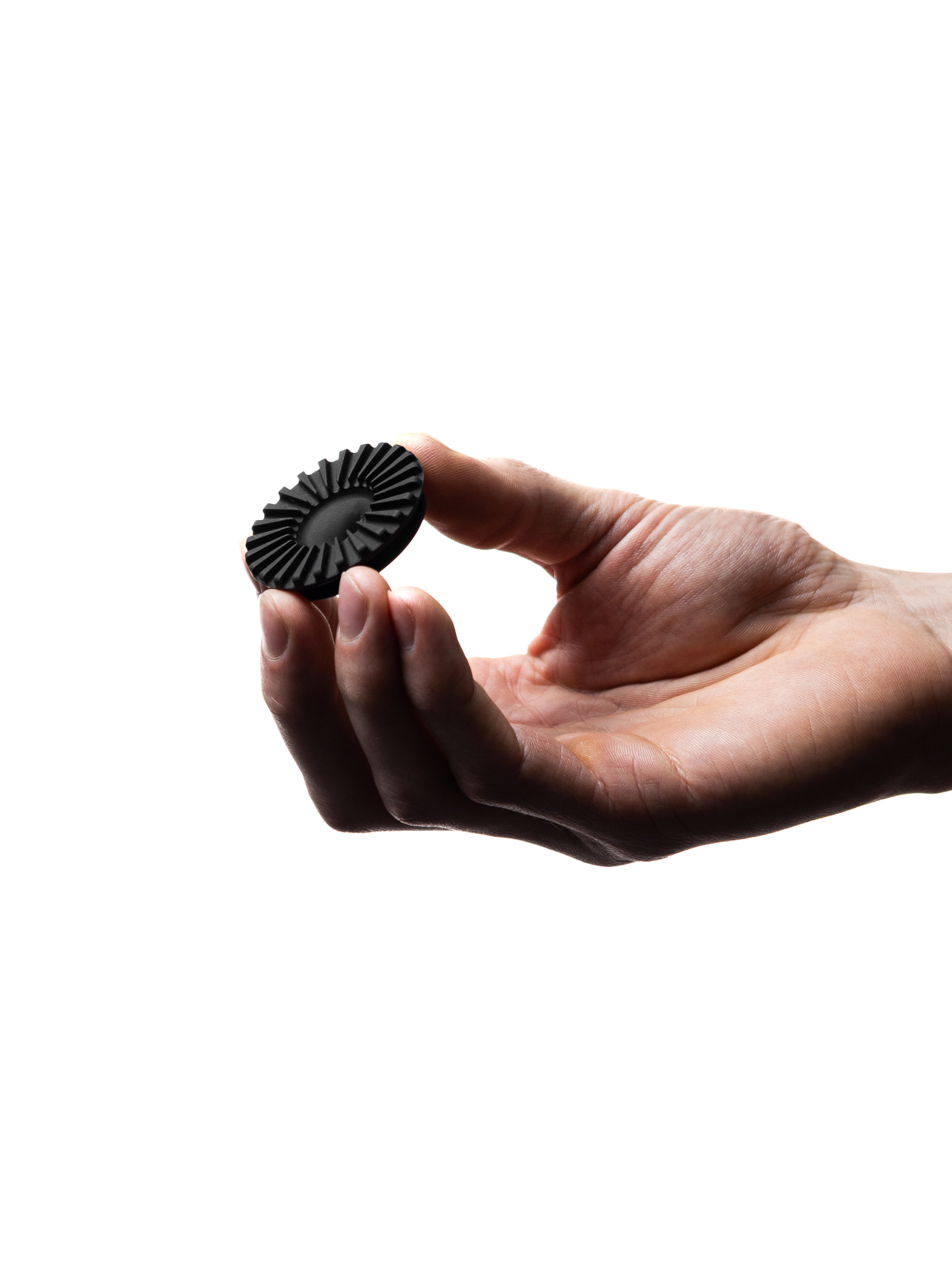 A clean white-background shot of a hand gently holding the black OREA #4 Medium Flow Regulator, showcasing its finned silicone design and the precise center hole that controls water drainage.