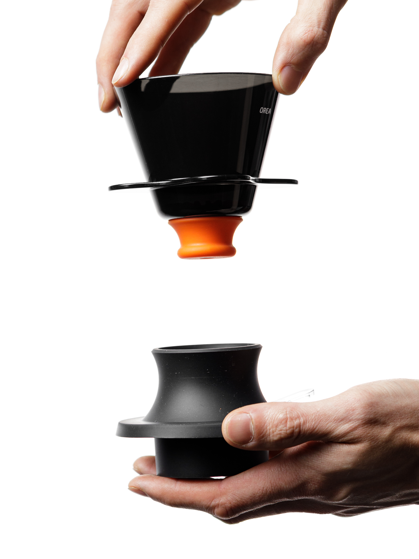 A dynamic studio shot of a hand lowering the glossy black OREA O2 Darth Black Brewer—fitted with the vibrant orange #8 Regulator—into its matte black base, highlighting the striking color contrast and modular design.