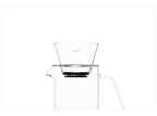 A clean studio shot of a clear OREA O2 brewer resting directly on the rim of a clear glass pour-over carafe, showcasing its flat-bottom design and universal fit for a seamless brewing setup.