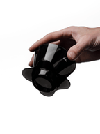A hand holding the compact OREA O2 brewer angled upwards, clearly displaying the open bottom and wide base designed to direct water centrally through the coffee bed for a balanced brew.