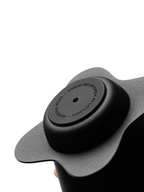 An extreme close-up of the matte black, textured base plate of the OREA O2 brewer, featuring the minimalist, laser-engraved circular text reading "DESIGNED BY OREA IN LONDON", showcasing premium build quality.