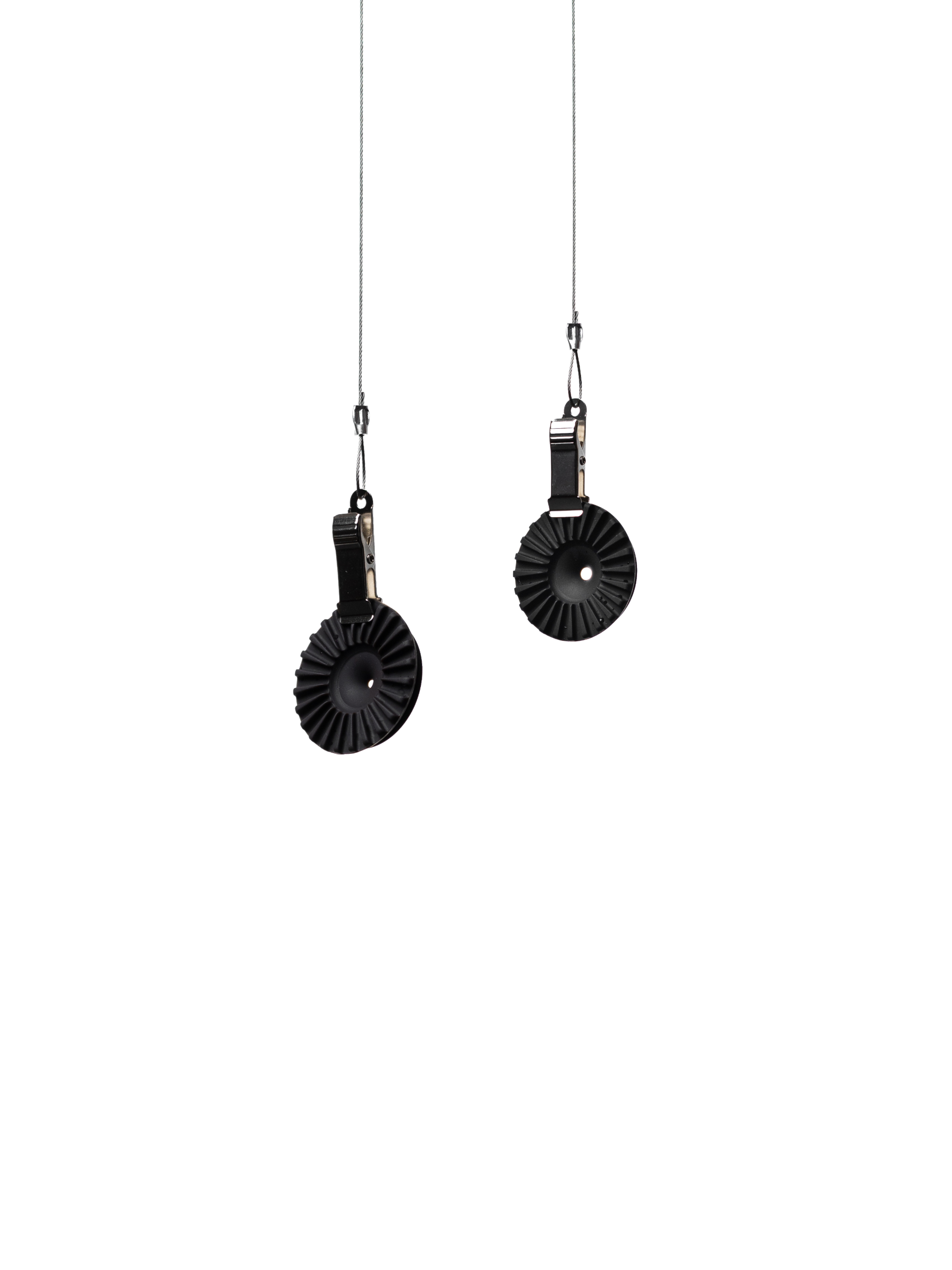 A split-panel studio shot of two black OREA #4 Medium Regulators suspended by metal clips on thin wires against a seamless white background, highlighting the sleek, industrial design of these silicone flow-control discs.