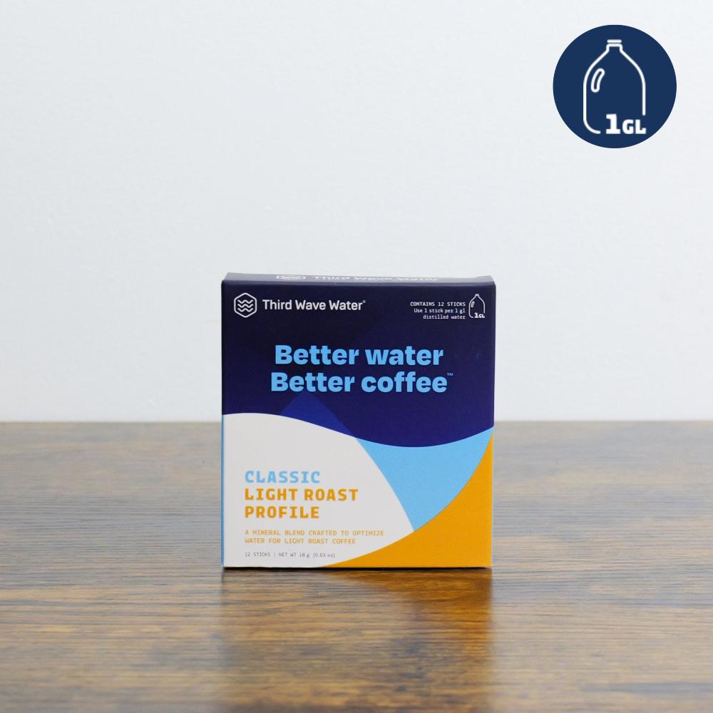 A square box of Third Wave Water minerals sitting on a wooden surface. The packaging is dark blue, white, and yellow, labeled "Better water Better coffee" and "Classic Light Roast Profile," in a white background and above a wooden table in Canada.