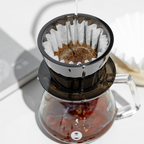 Fresh coffee dripping from an amber black Timemore Crystal Eye B75 plastic dripper during pour-over brewing.