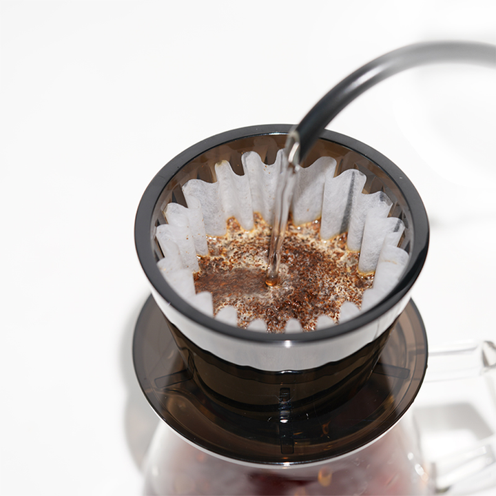 Timemore Crystal Eye B75 plastic dripper in Amber Black, with brewed coffee dripping through the bottom.