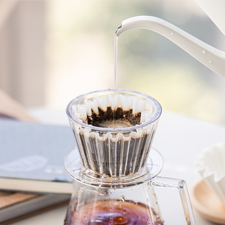 Fresh coffee dripping from a clear Timemore Crystal Eye B75 plastic dripper during pour-over brewing.